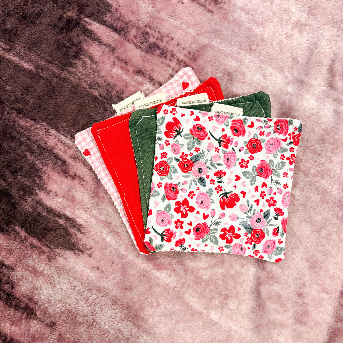 Stack of colorful fabric jar grips with floral patterns on a textured surface