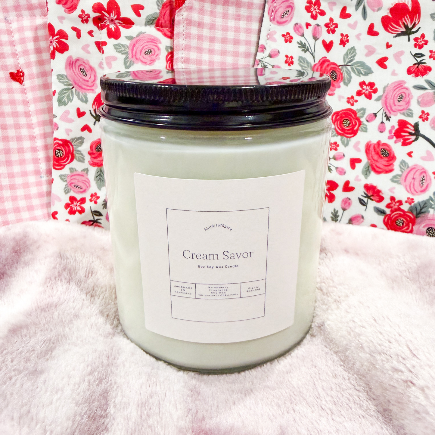 Candle labeled 'Cream Savor' with a floral patterned fabric background