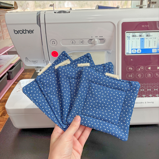Hand holding blue polka star fabric coasters in front of a Brother sewing machine.