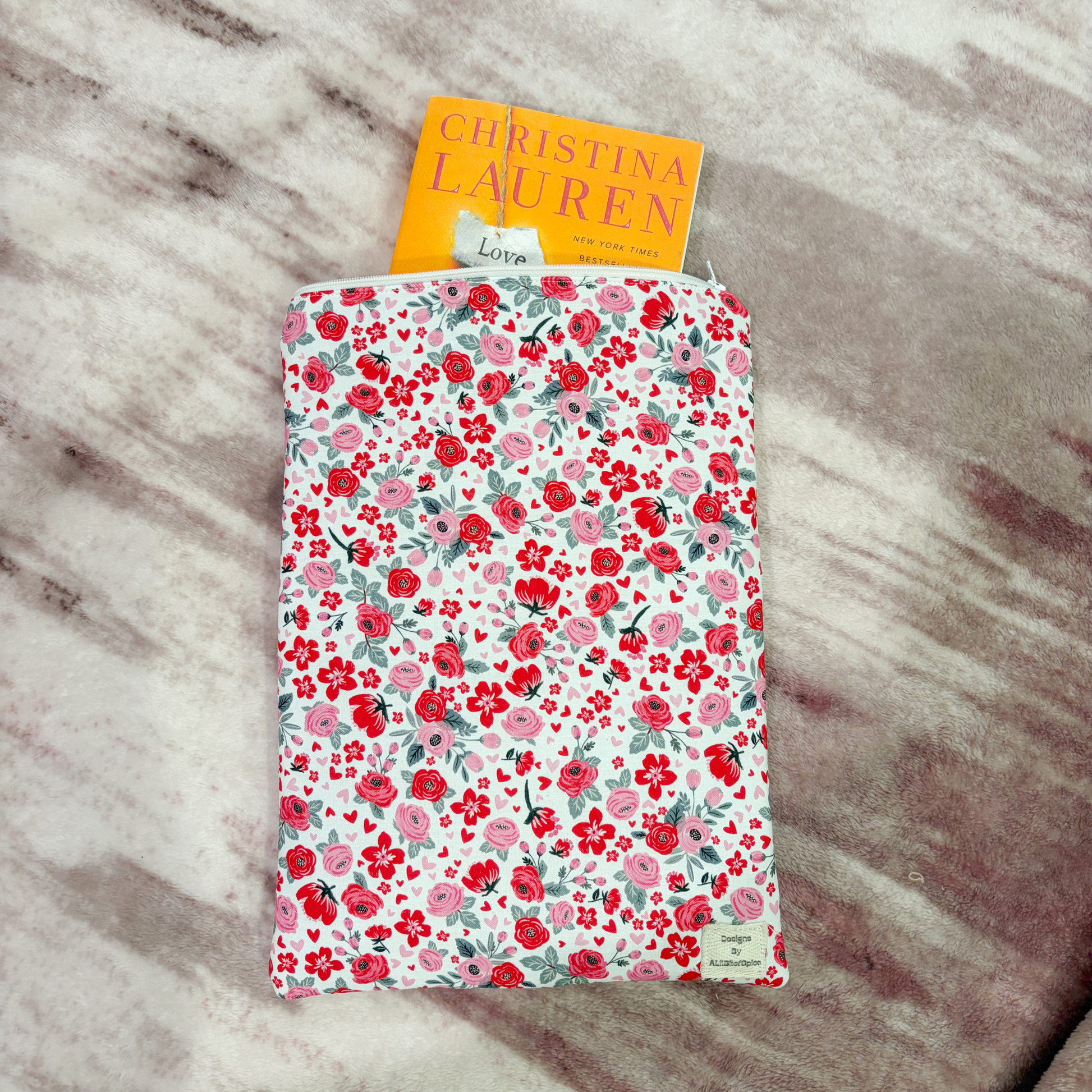 Floral-patterned book sleeve with a book titled 'Christina Lauren' on a marble surface